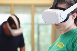 A pair of Two Summers students wearing Oculus Rift VR equipment play mini-golf together in the virtual world